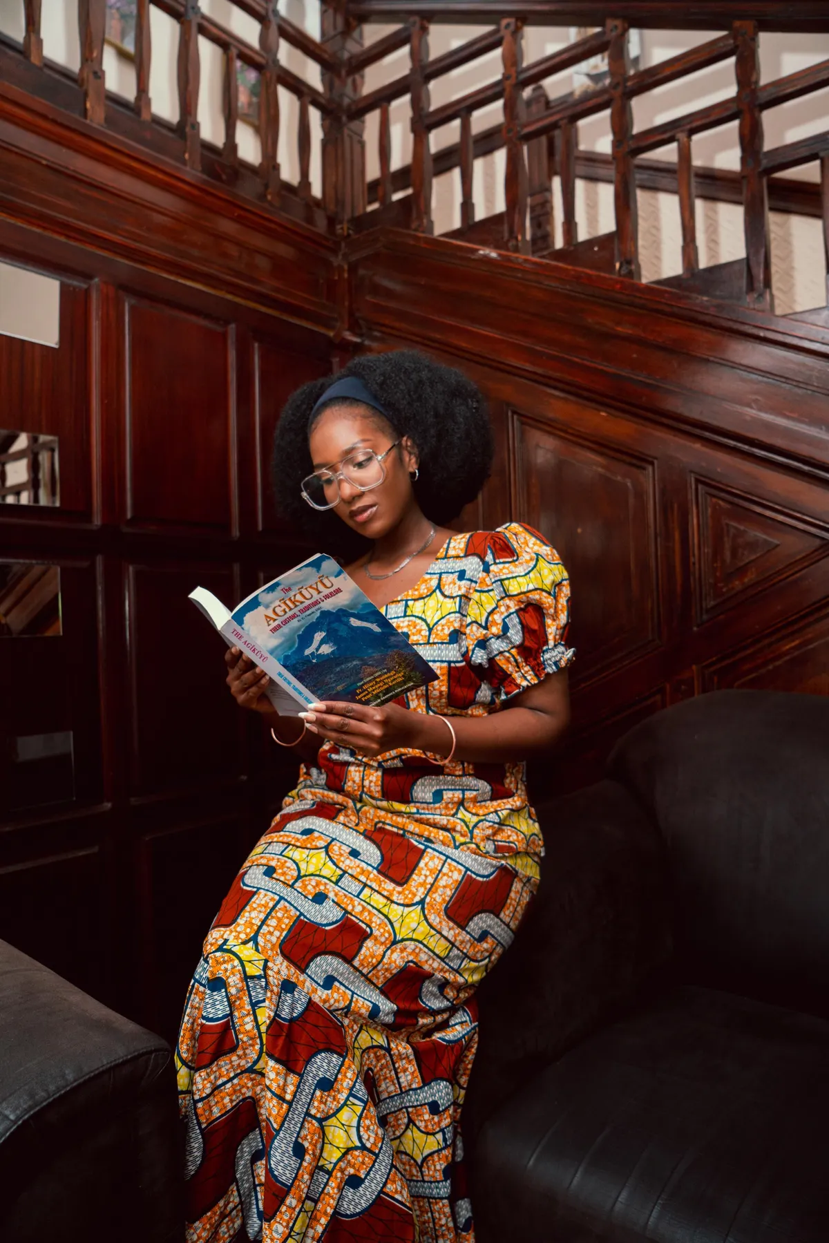 Femme en pagne lisant un livre avec ses lunettes